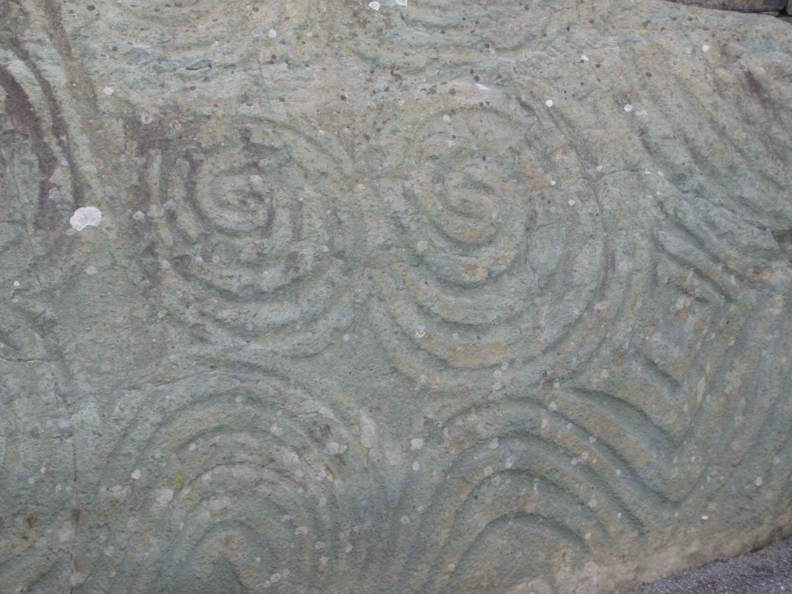 Detail of Newgrange's entrance stone, its surface carved with interlocking triple spirals and lozenges around 3200 BC. Photo: Mark McElroy, CC BY 2.0, via Wikimedia Commons.